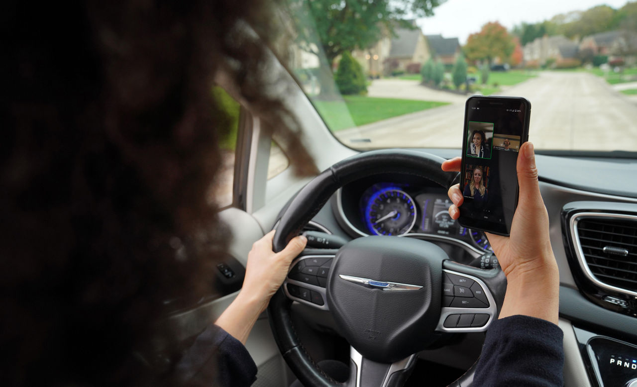 Woman holding a phone while on a conference call while driving
