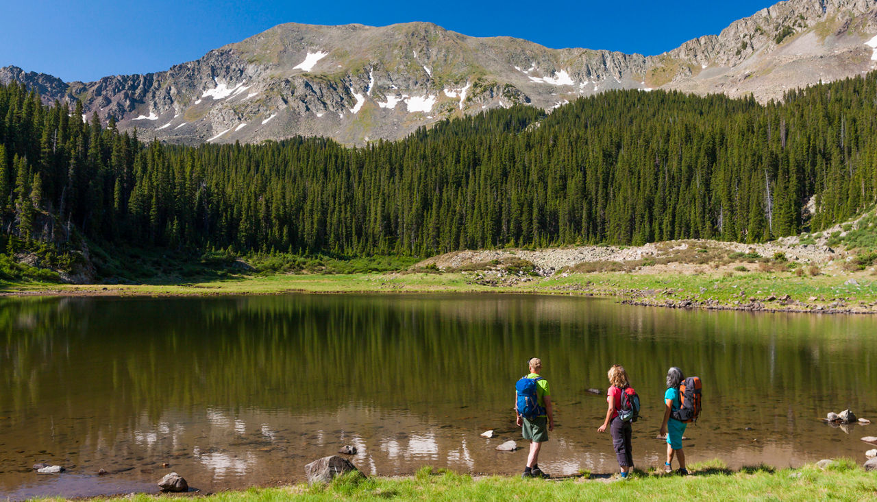 Hikers admiring still lake in rural landscape