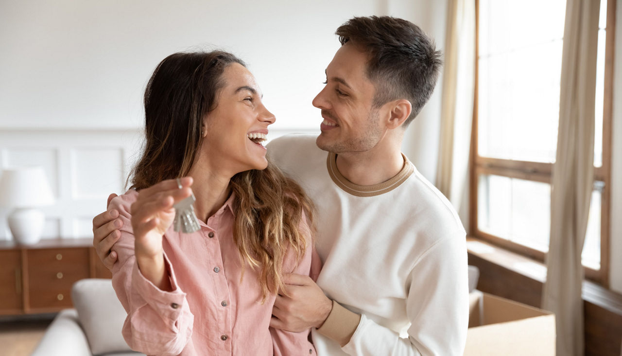 Happy homeowners cuddling, amazed by real estate purchase.