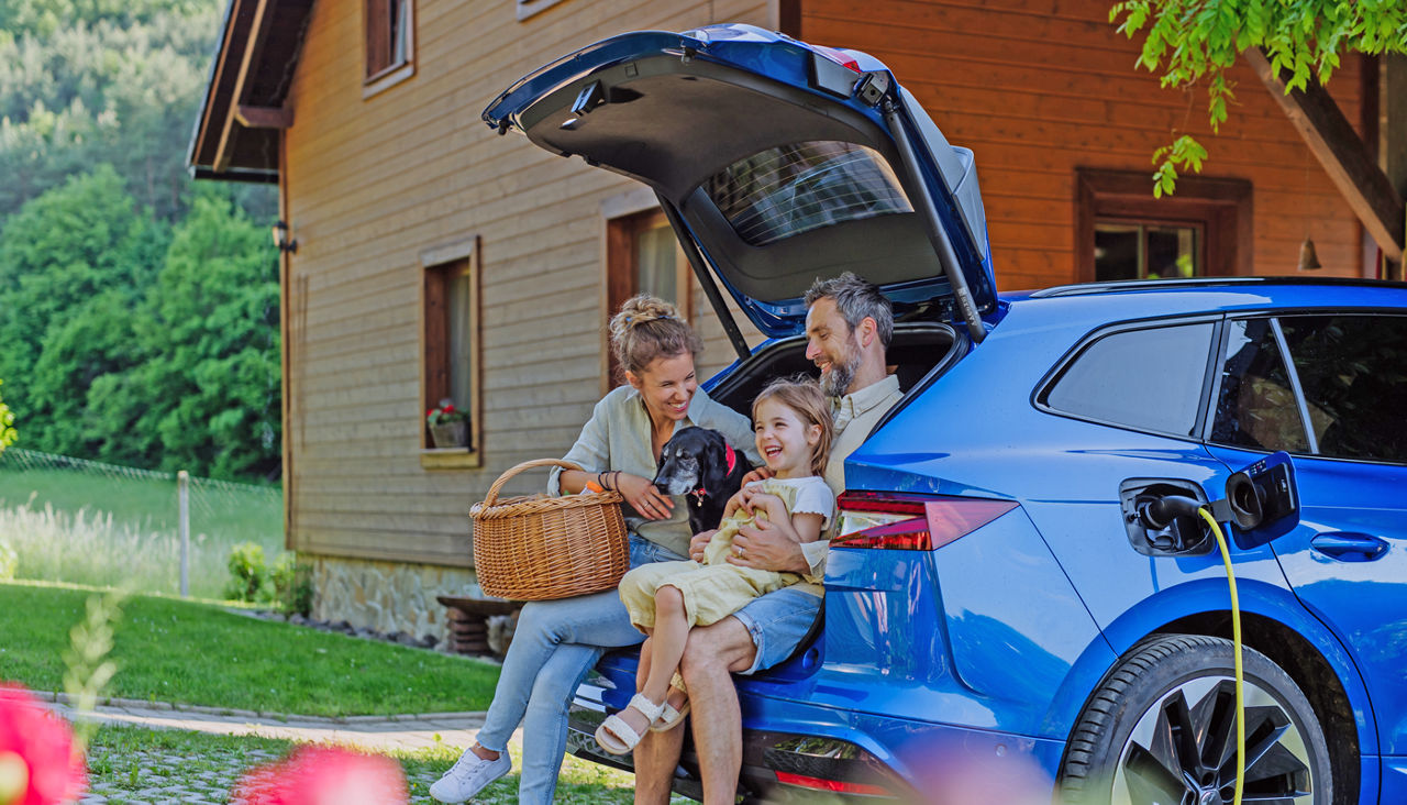 Happy family sitting in the back hatch of their car waiting for it to charge