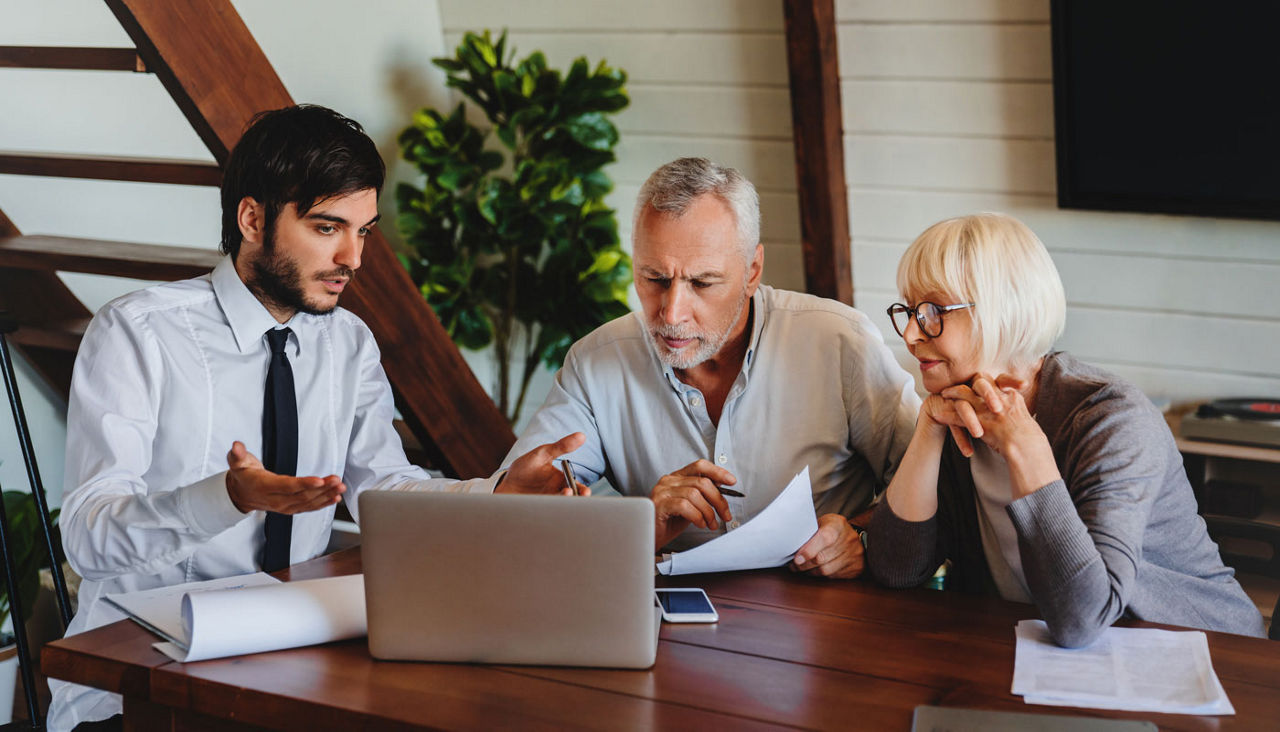 Senior couple sitting with a financial planner, discussing retirement
