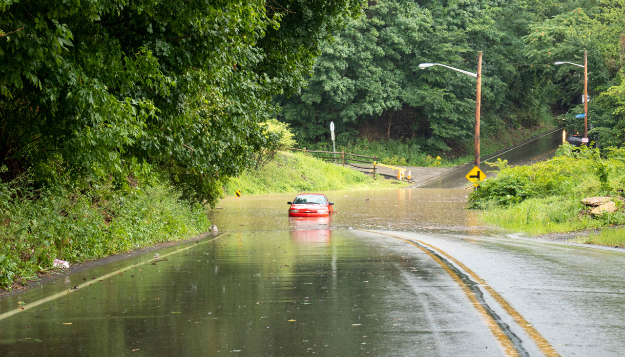 Stalled car half submerged in water as it tried to drive on a flooded road