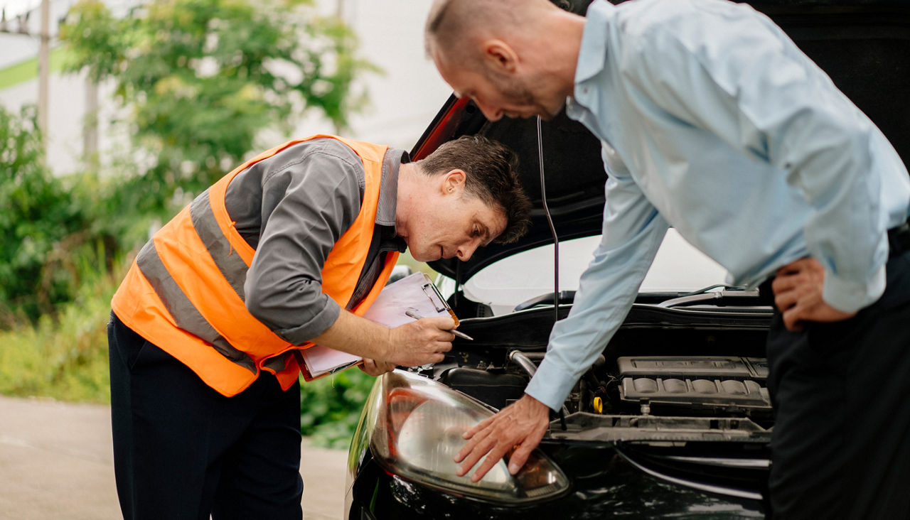 Two men reviewing the headlights of a car