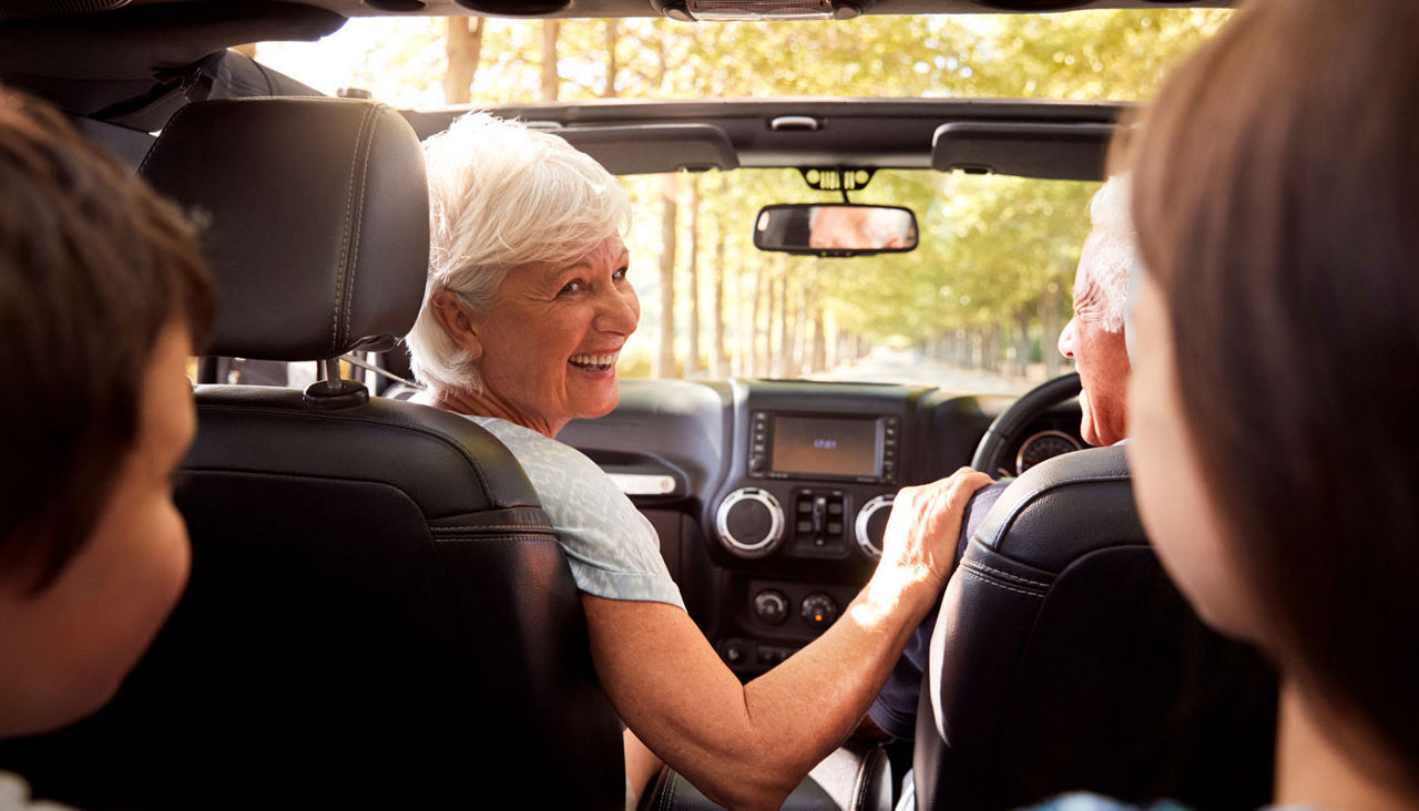 Grandparents And Grandchildren Driving In Open Top Car