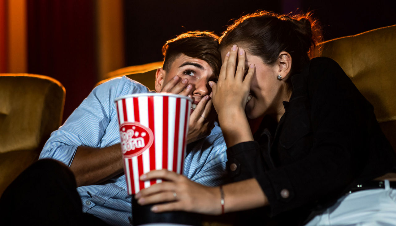 A couple watching movie shocked and eyes close in the movie theater cinema.
