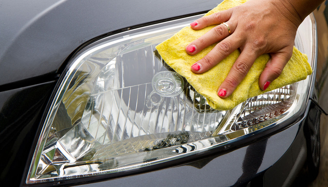 Closeup of hand wiping headlight with rag