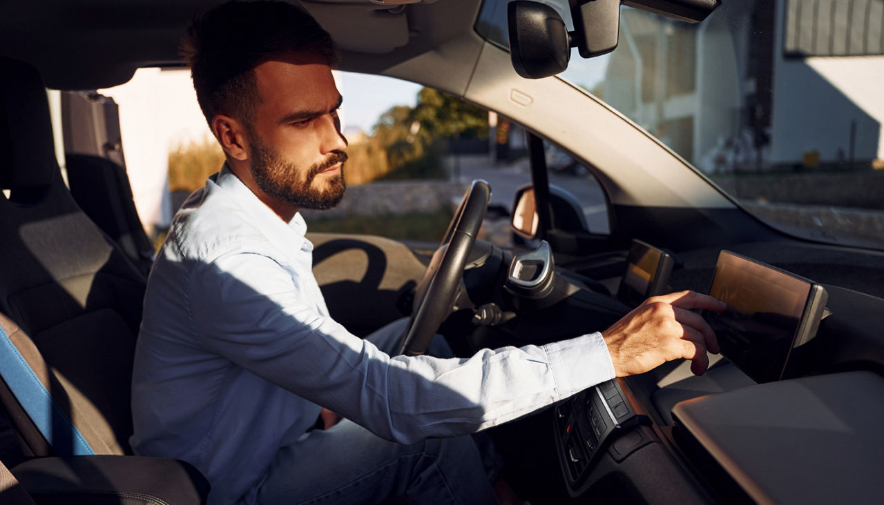 Man sitting in electric car pressing buttons