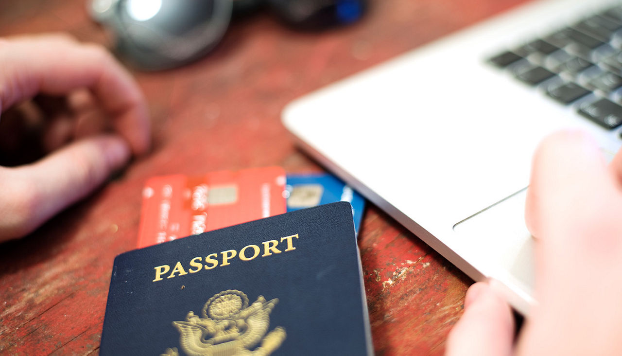 Close up of passport, credit or debit cards, and a laptop computer.