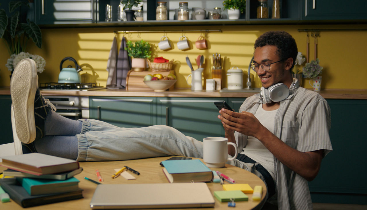 Smiling male on his cell phone in kitchen relaxing