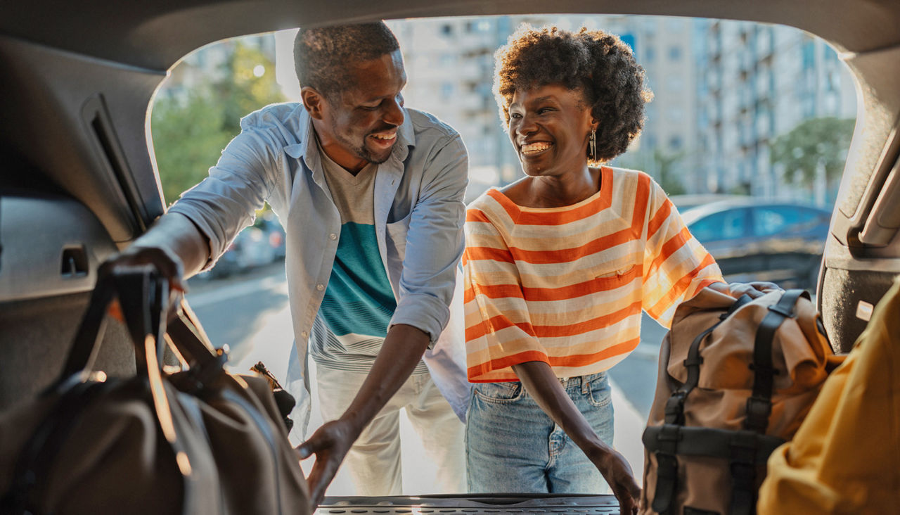 Couple loading luggage into car in urban setting