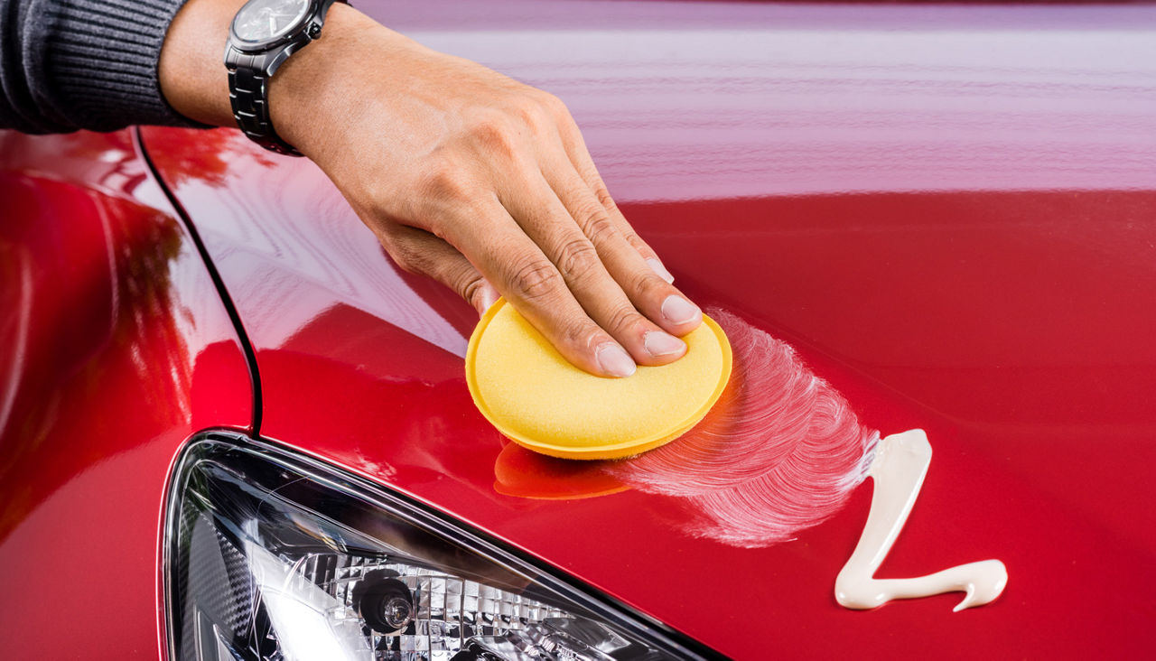 Hand shown waxing or polishing a red car