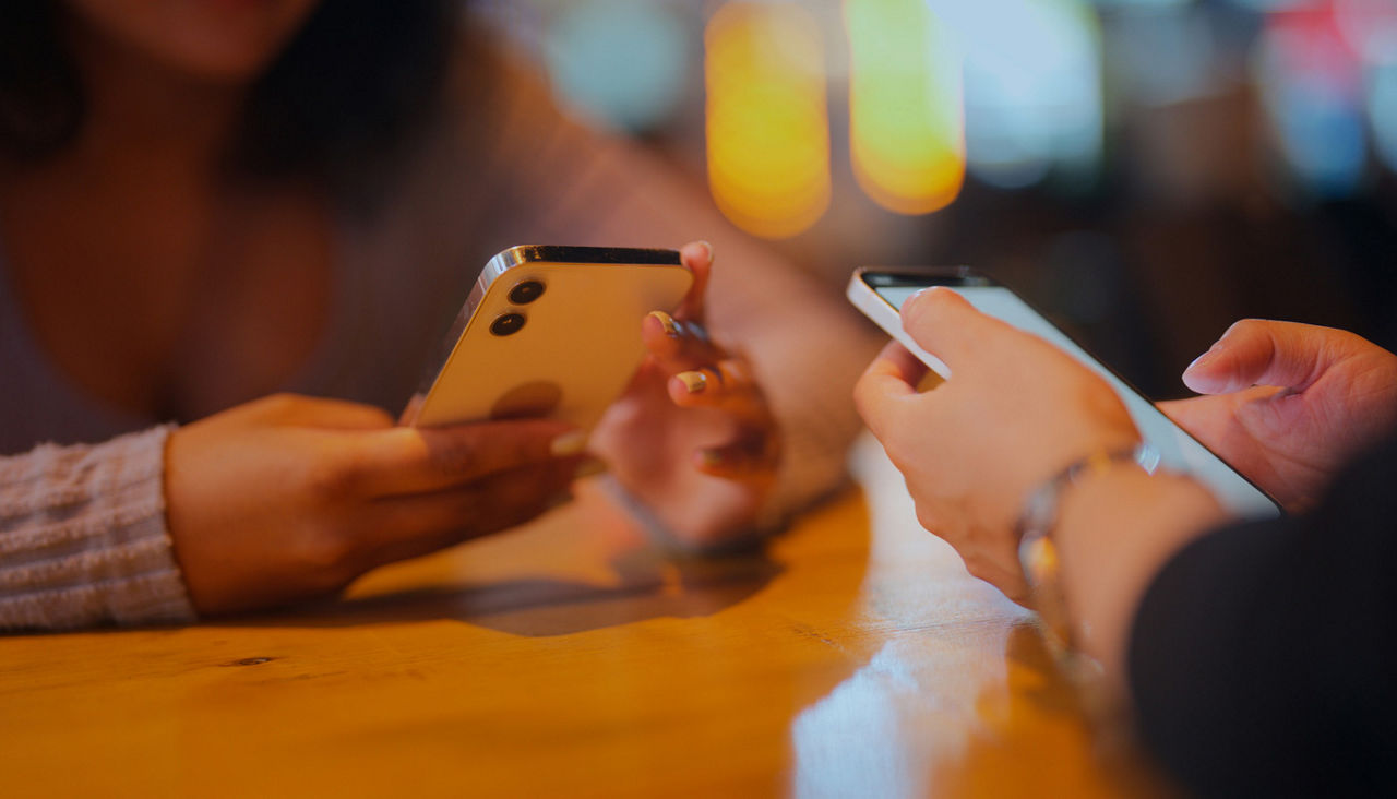 Two people holding phones in their hands facing each other