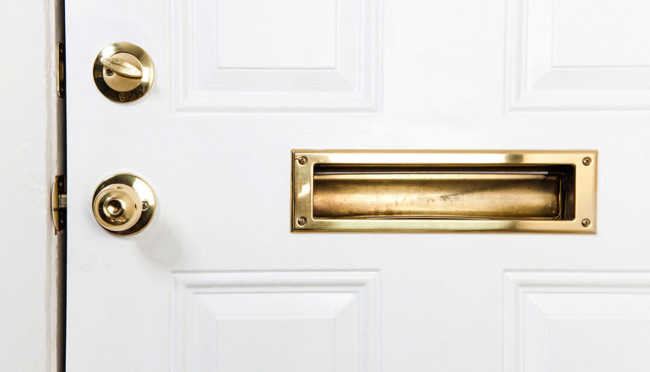 A front door with mail slot, doorknob and deadbolt lock
