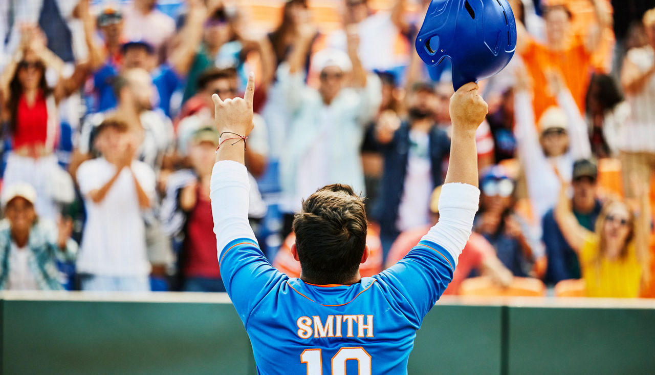 Rear view of professional baseball player saluting cheering crowd after hitting home run during game in stadium