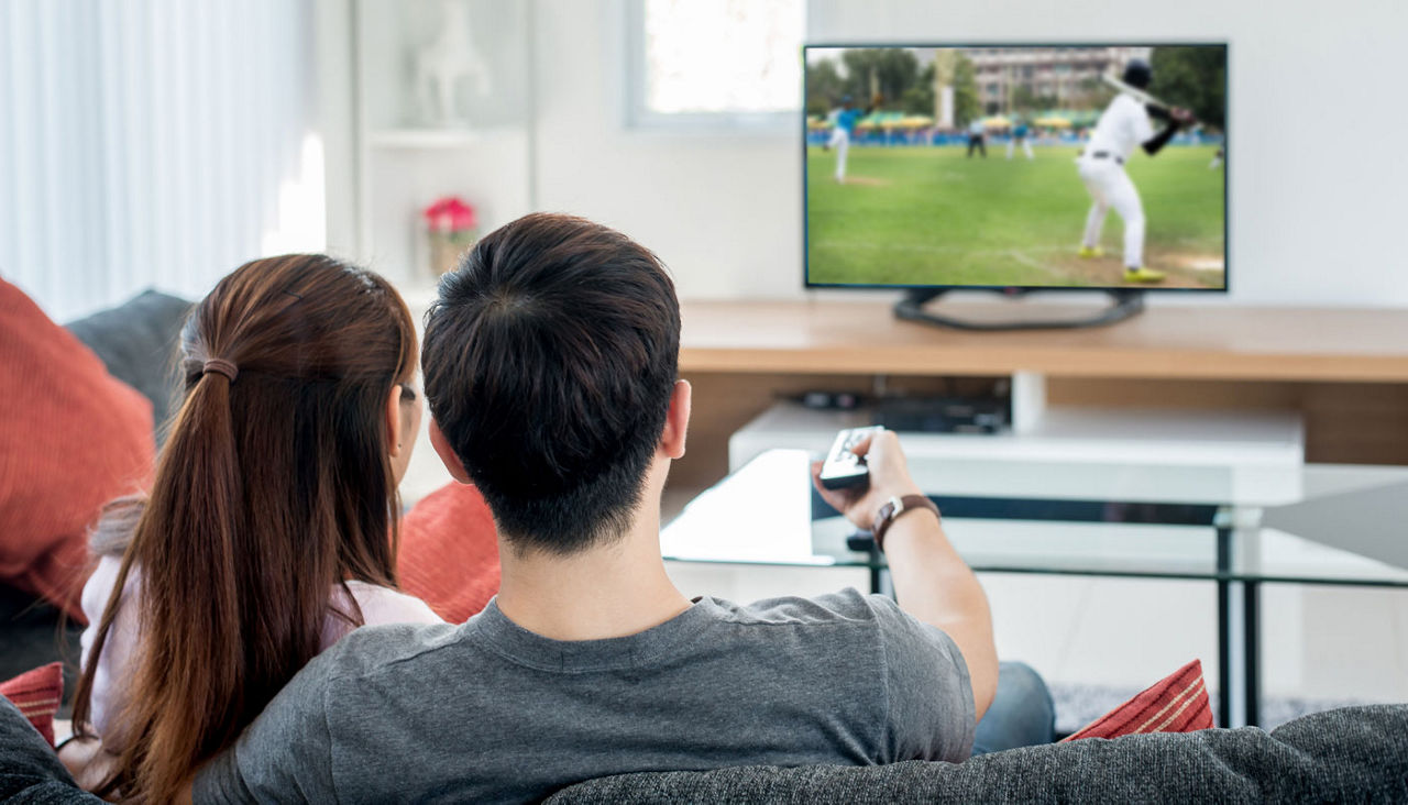 Young couple waching baseball sport on tv at home