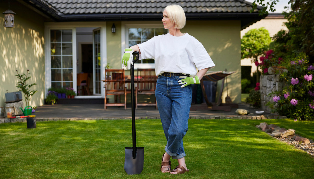 Portrait of middle aged woman standing with shovel in garden looking away