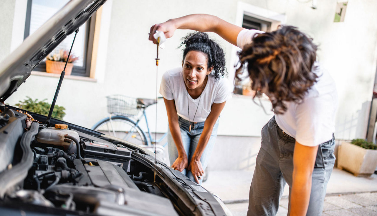 Mother watching her son check the oil in the car