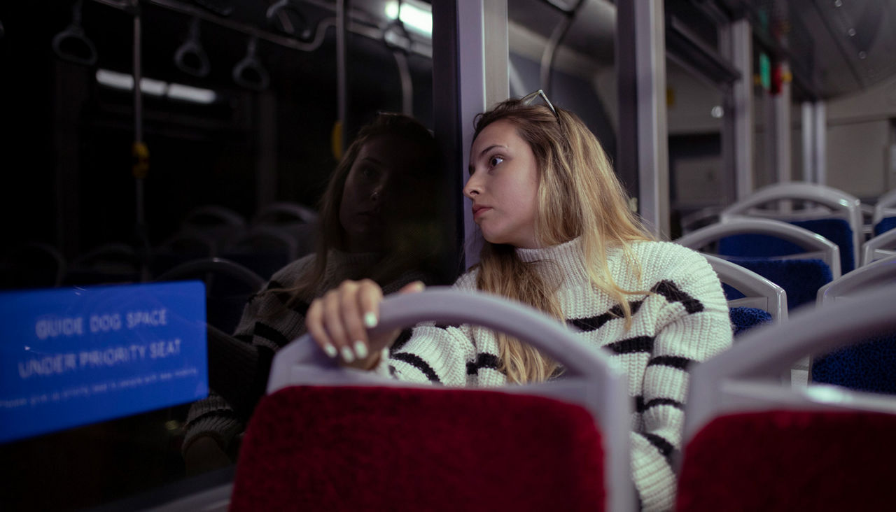 Woman looks out the window of a bus during a night ride.