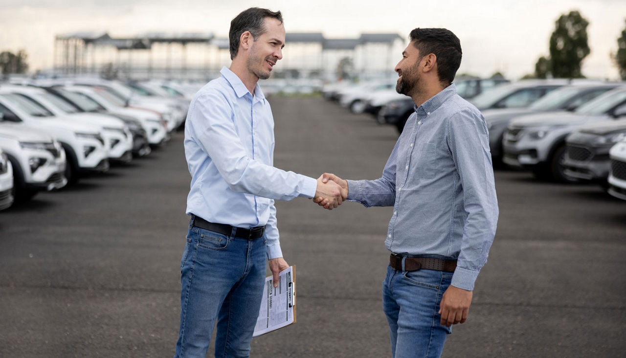 salesman handshaking with a client after buying a car at the dealership