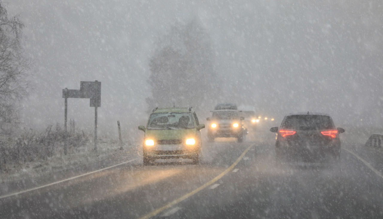 Driving in highway traffic with winter sleet and snow creating low visibility conditions