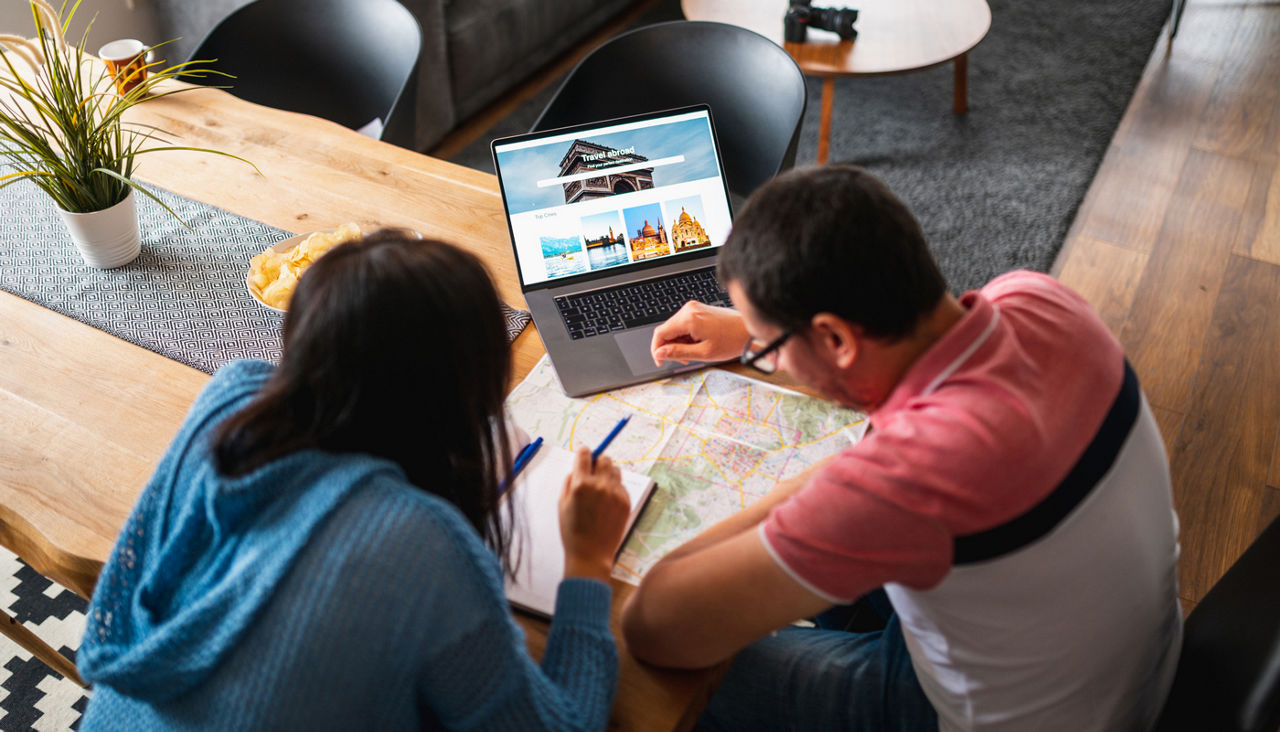 Couple mapping out their travel with a map and a laptop