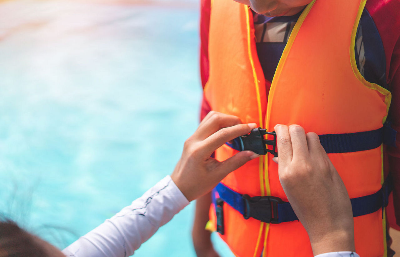 Mother helping her son to wear life jacket 