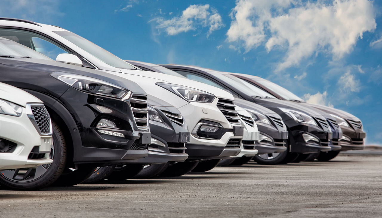 A row of dark and muted color cars in a lot