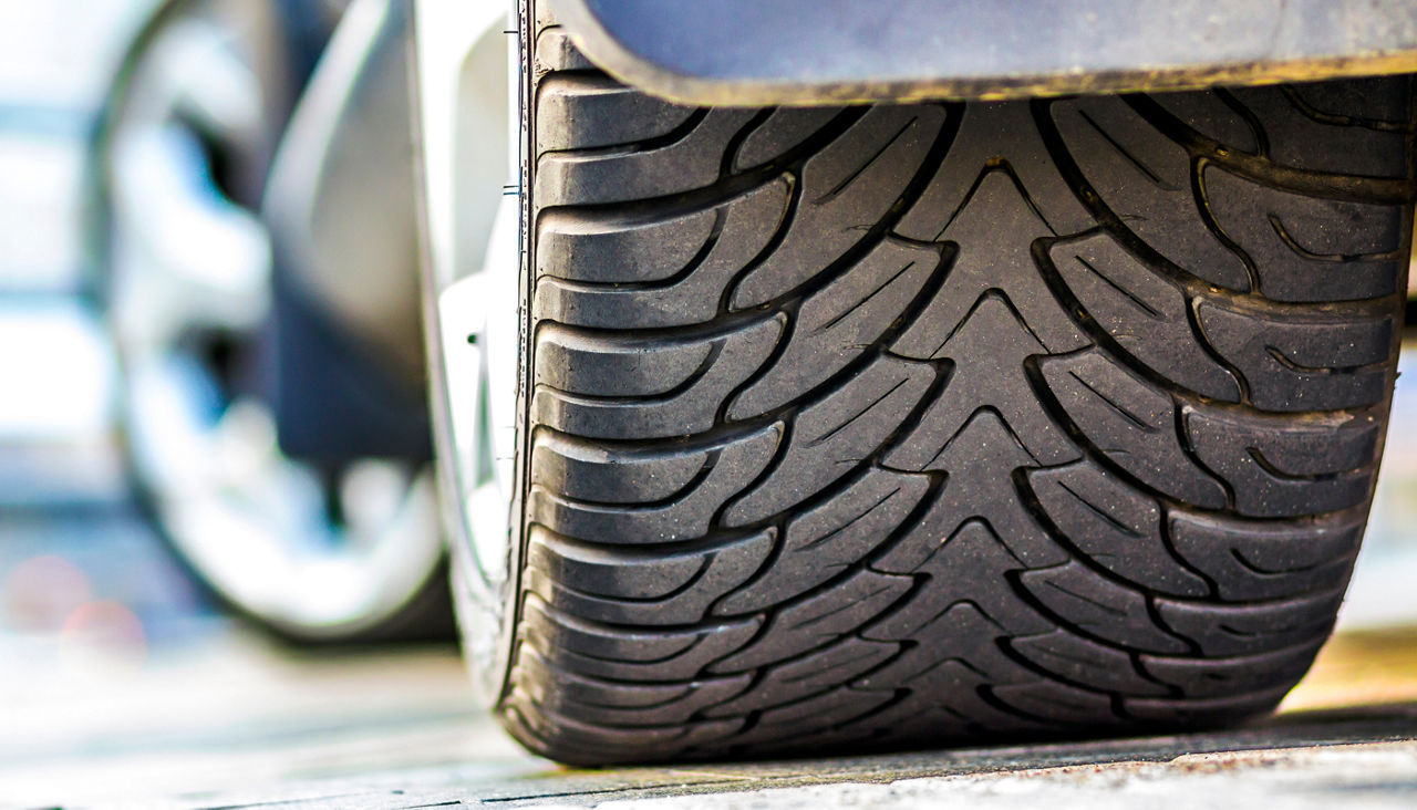 Close up of car tire tread on a parking lot surface.