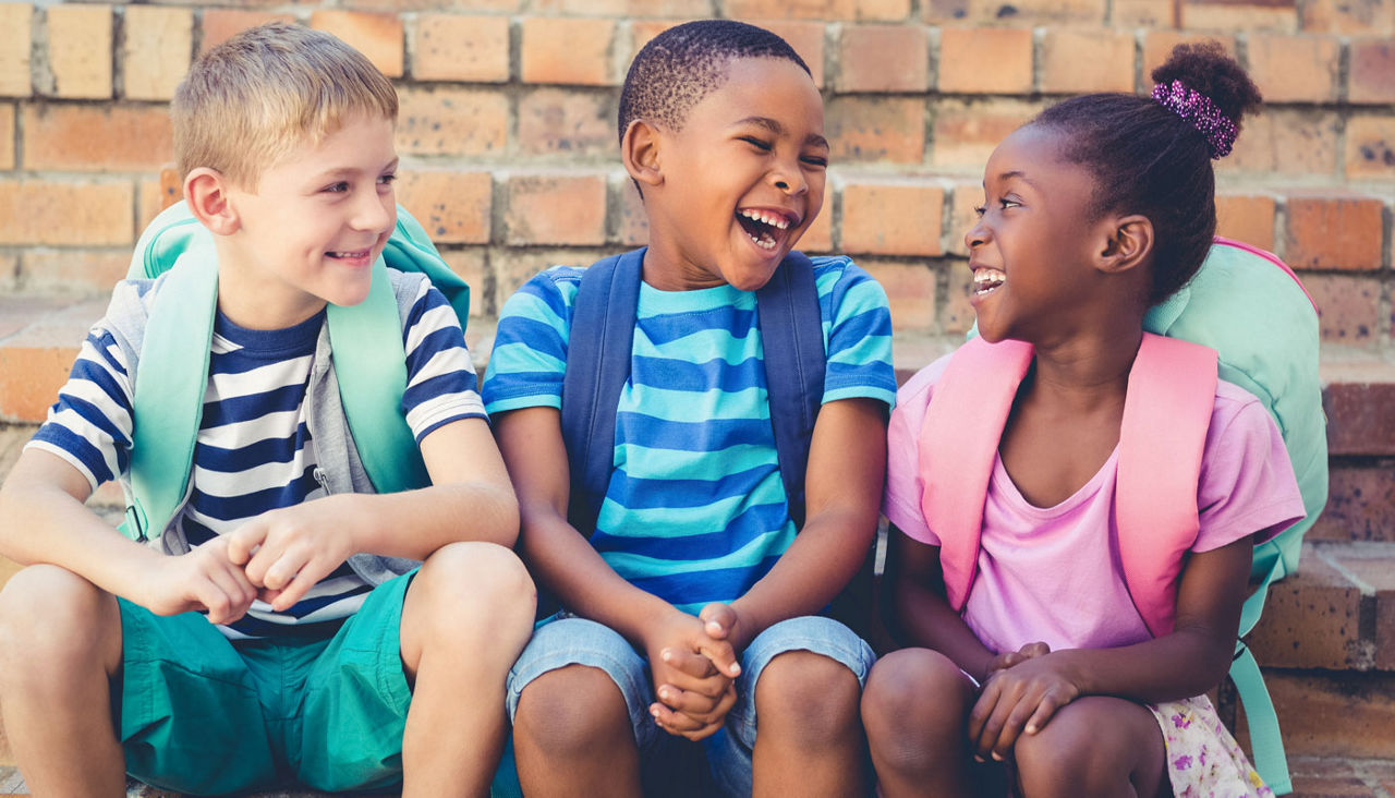 Happy mixed race school kids sitting together on staircase