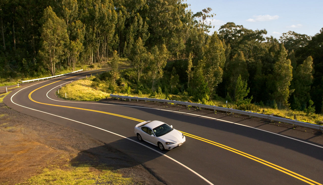 White car driving on a curvy road in the mountains