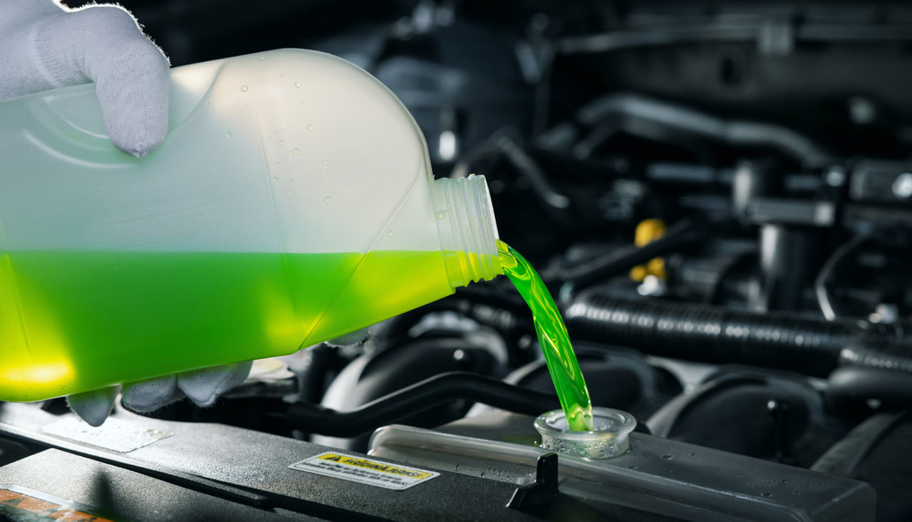 pouring antifreeze coolant liquid into car engine radiator