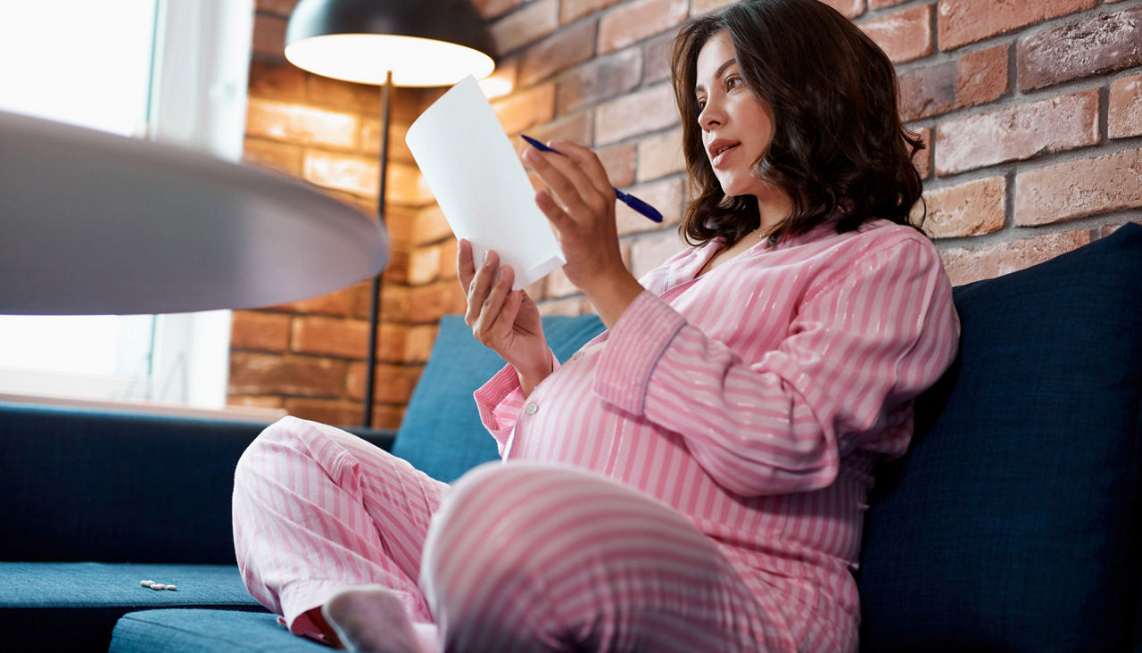 young caucasian pregnant woman rereads all points in packing list, she will give birth soon