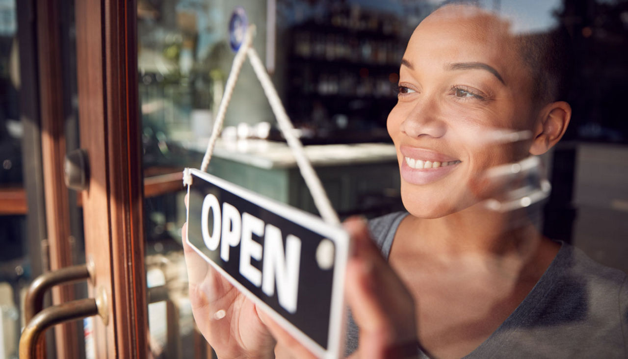 Owner of start-up coffee shop or restaurant turning around Open sign on door 