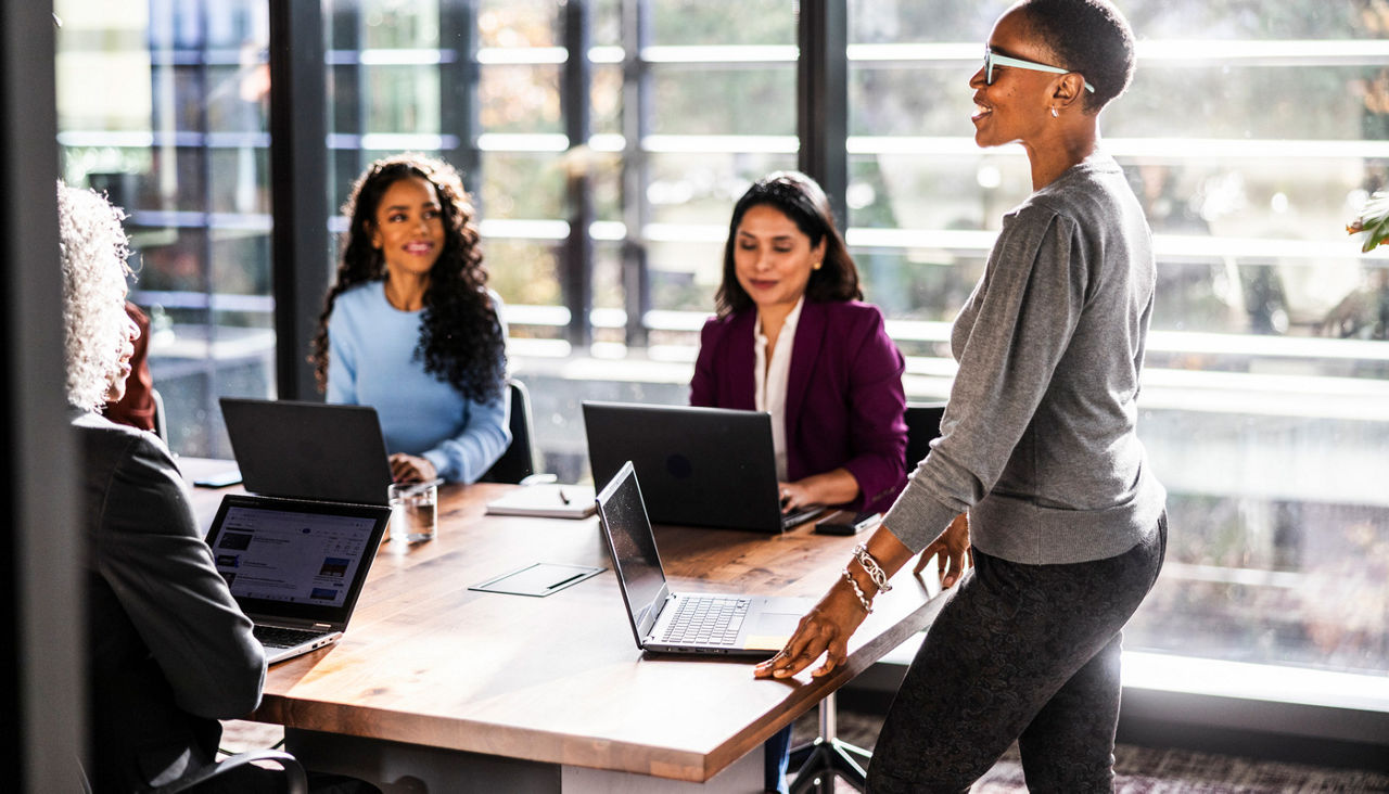 Female business owner speaking to office workers in modern conference room