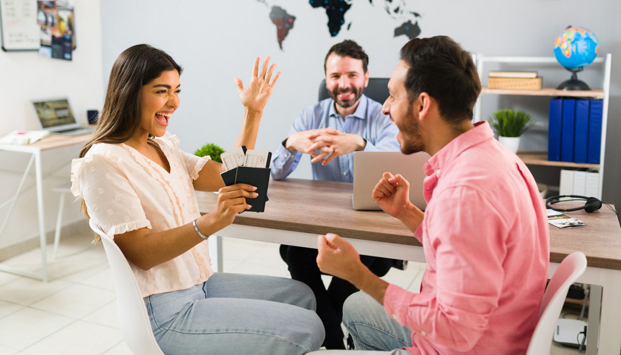 Tourists celebrating buying an exciting trip with travel agent and documents