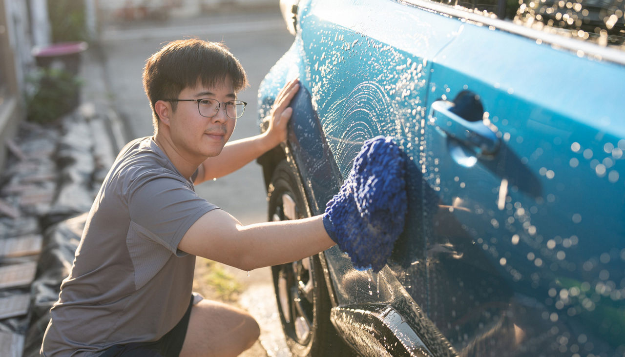 adult man washing car in yard