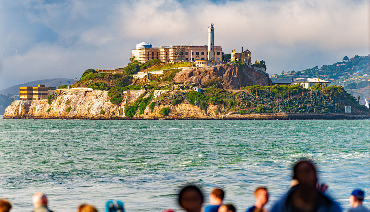 A group of visitors looks out over the water to see Alcatraz Island.