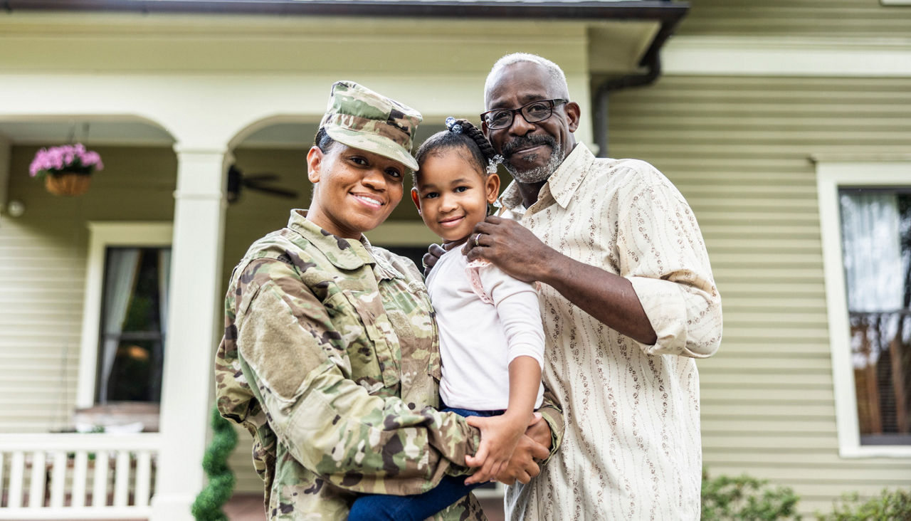 Portrait of female U.S. soldier and senior father in front of home