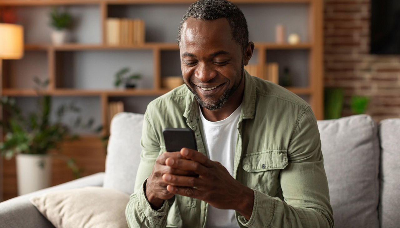 middle aged man reads message on phone, watches video