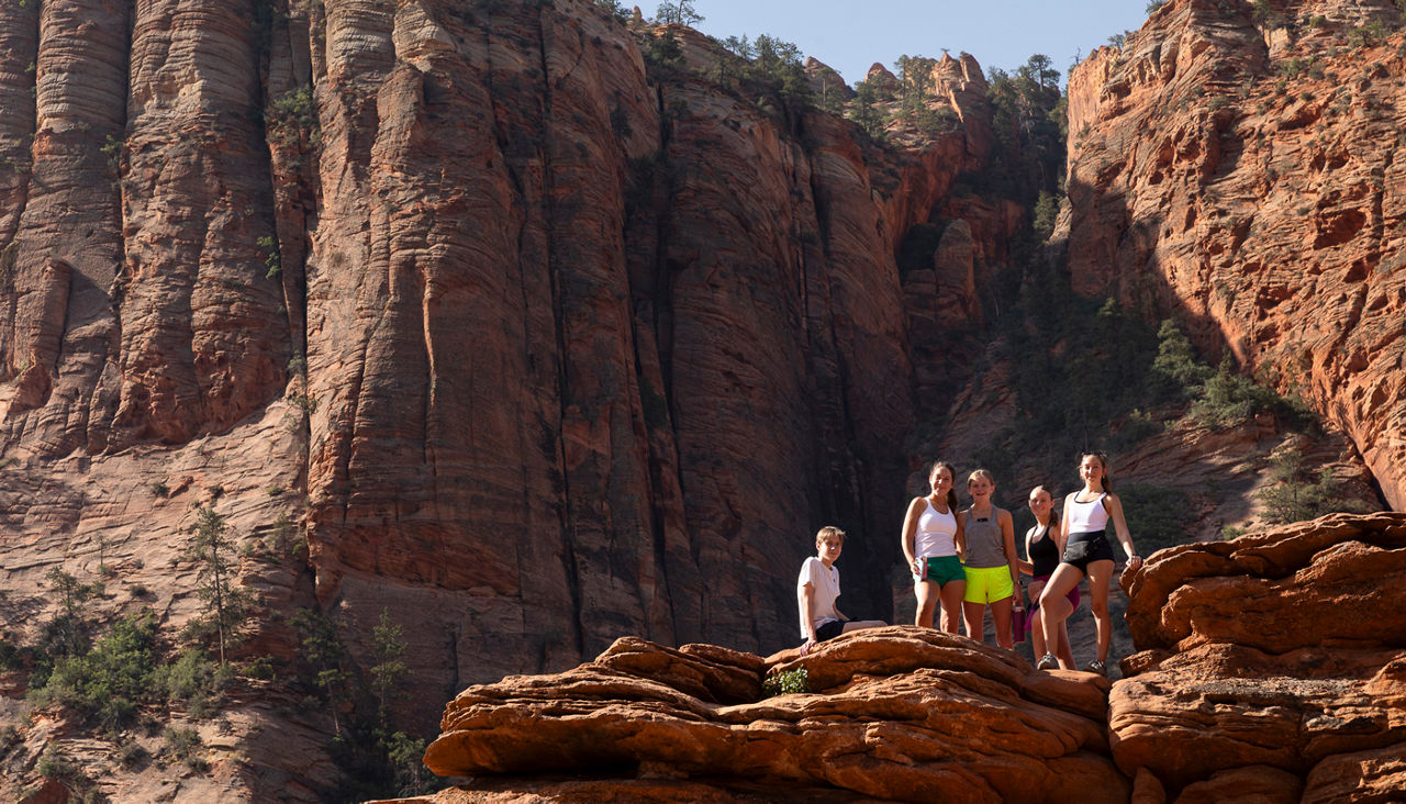 Group of teens standing atop mountain ledge in Zion National Park