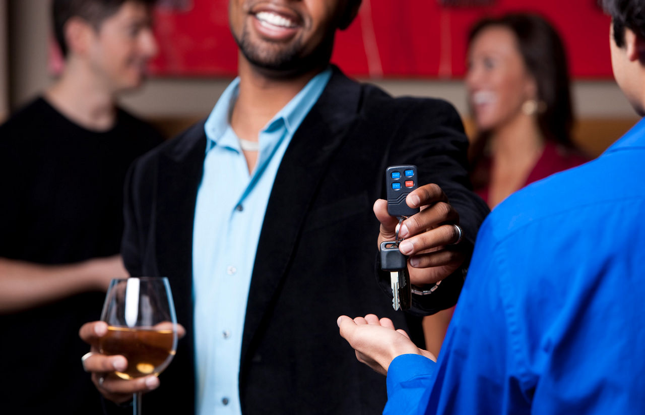 Man hands over the keys while holding a glass of wine at a party