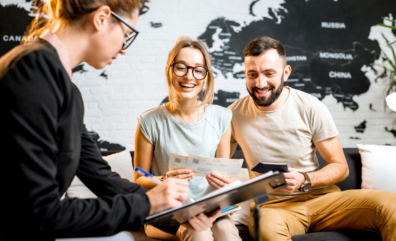couple sitting with manager at the travel agency office prepairing for a summer vacation