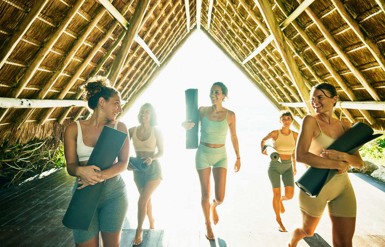 female friends finishing yoga class in ocean front pavilion at tropical resort