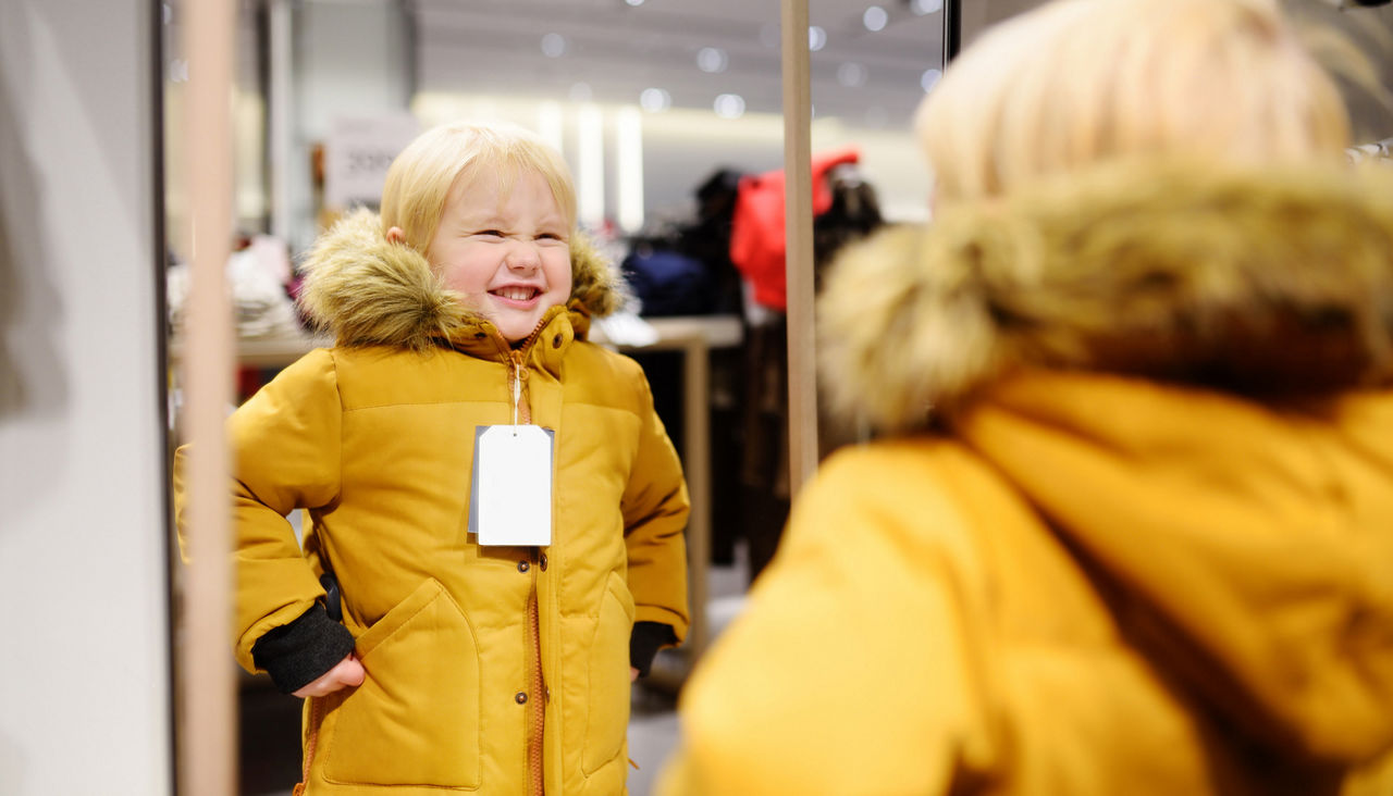 Cute little boy trying new coat during shopping