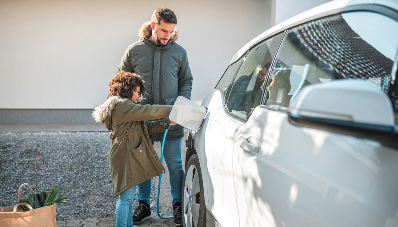 Father And Daughter Charging An Electric Car At Home 