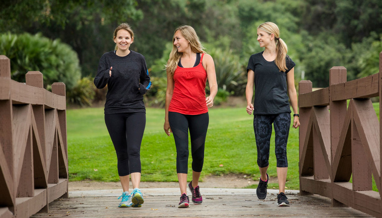 Group of three women in their 30s walking together outdoors.