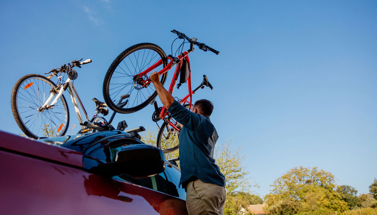 Young man dismounting bicycle of the roof of his vehicle