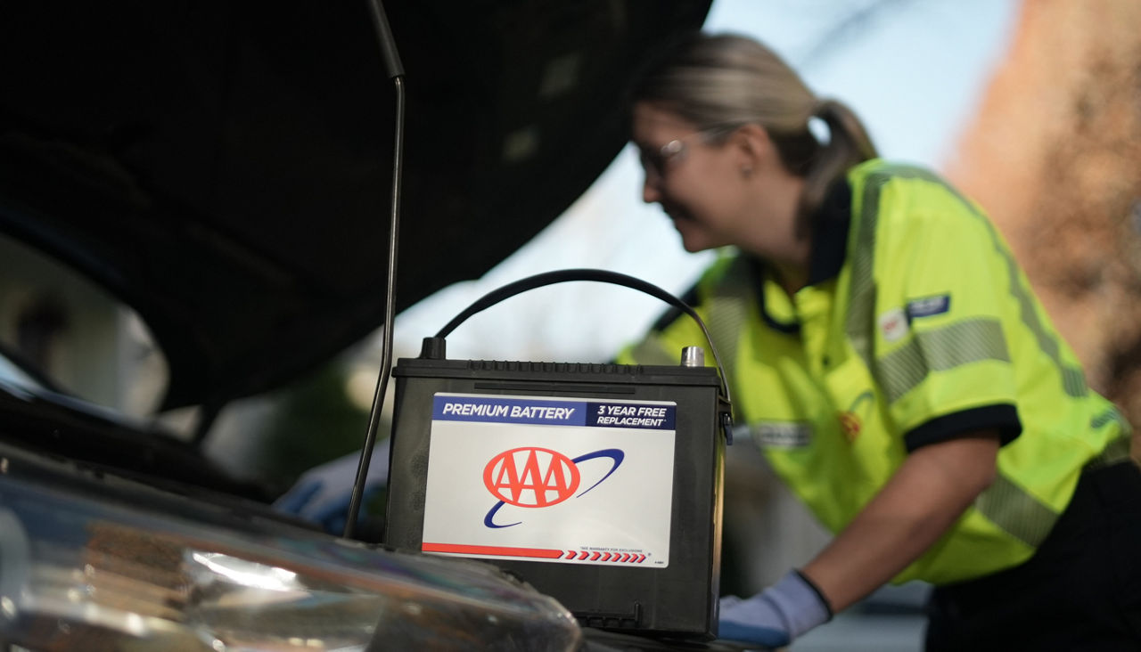 Mobile battery technician installing new AAA battery in vehicle