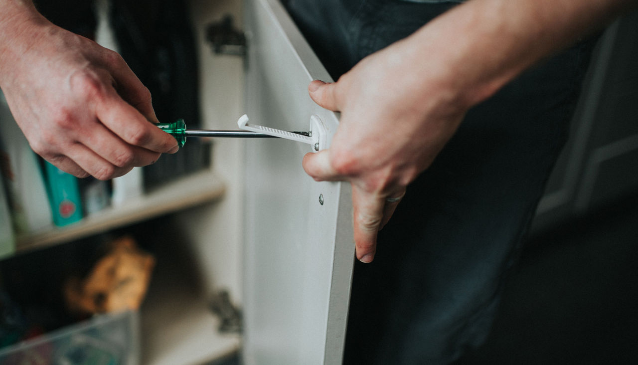 Male attaching child locks to a cupboard door