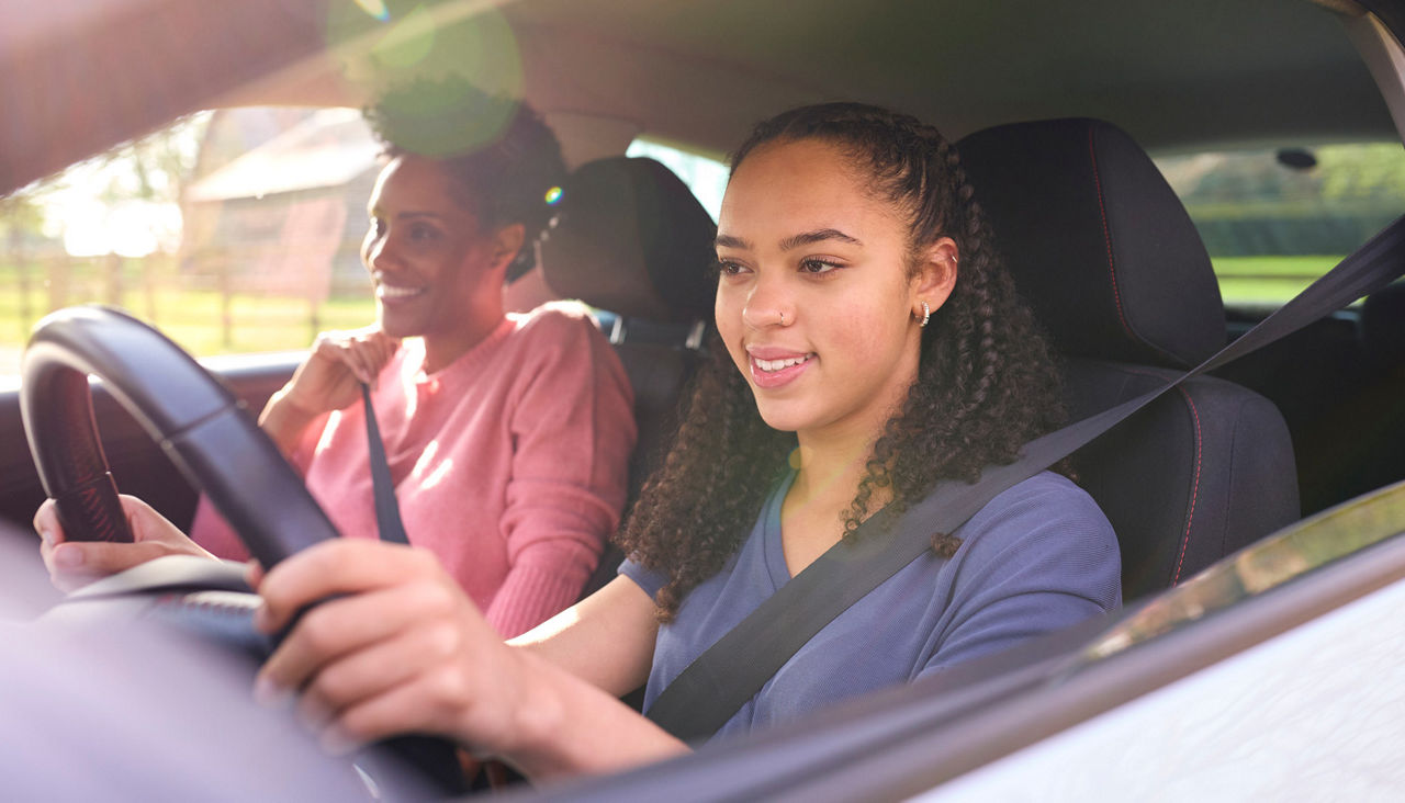 Teenage Girl In Car Having Driving Lesson From Female Instructor Or Parent